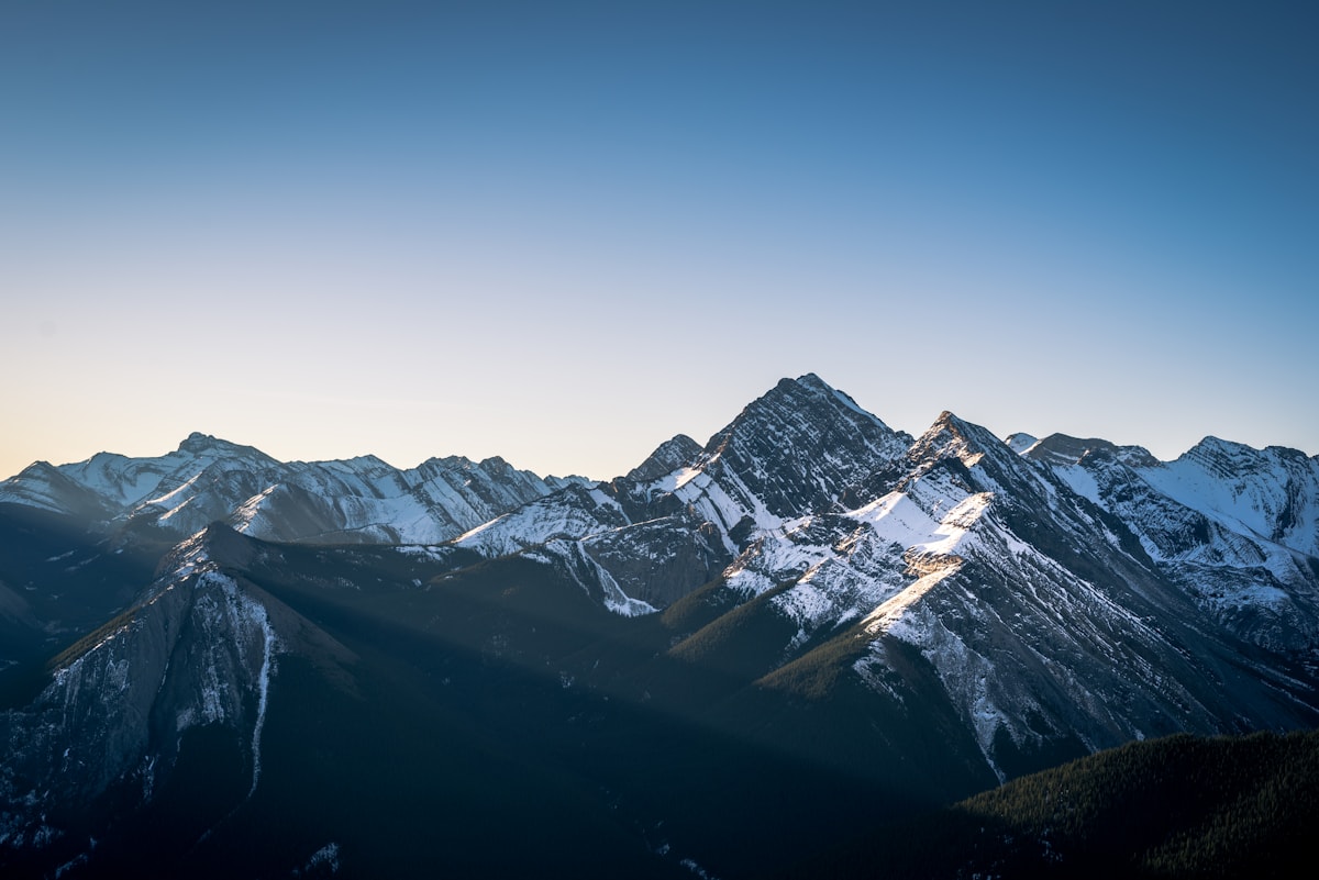 Dark mountain ridges with snow, under a clear sky at sunrise